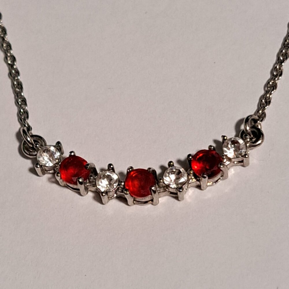 N R silver tone necklace with red and diamond like stones